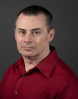 Male person in red shirt on dark background