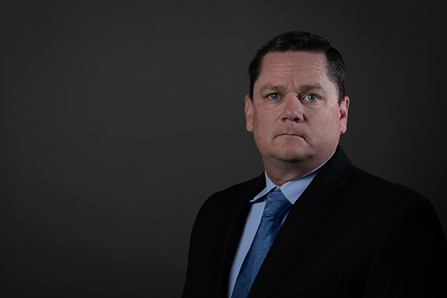 Male person in shirt, tie, and jacket on a dark background