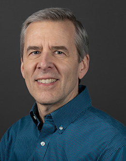 Male person in a blue shirt on a dark background